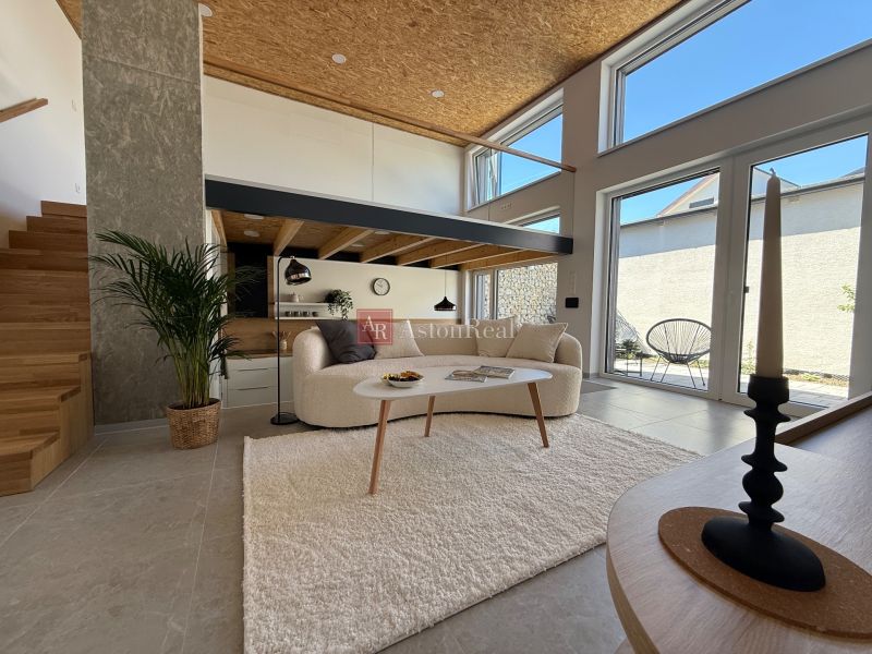 Living space in a family house with stairs, a sofa, and large windows to the terrace.