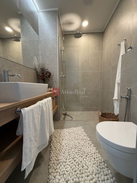 Bathroom in a family house with an open shower, sink, and decorative mat.