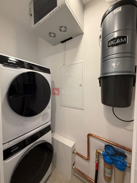 Laundry room in a family house: washing machine, dryer, BEAM central vacuum, and water filter.