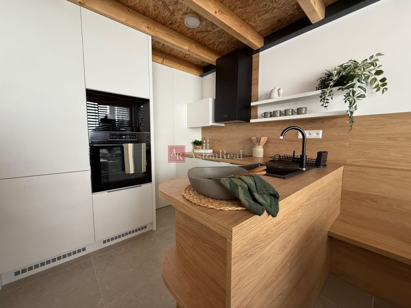 A kitchen in a family house with wooden decor, white cabinets, and plants.