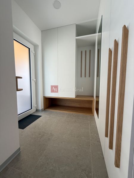 Entrance hall in a family house with a mirror, storage space, and light tiles.