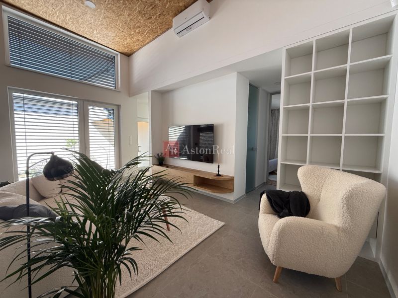 Living room in a family house with a cream armchair and a television, wooden decor flooring.