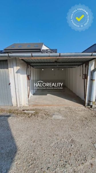 Garages in Senec with a metal gate and gravel access.
