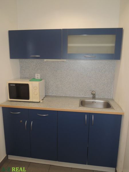 A kitchenette with blue cabinets and a microwave in the office.