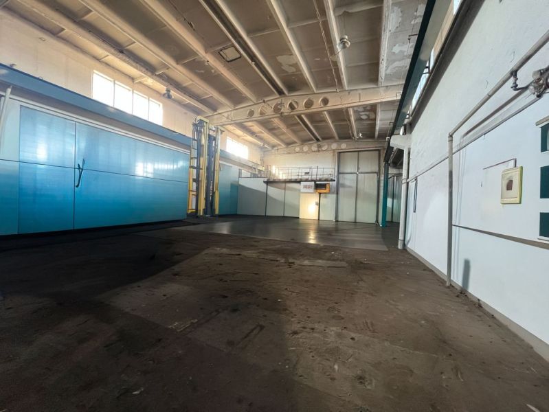 Production spaces with high ceilings, featuring light blue doors and pipes on the walls.