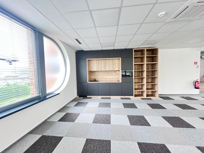 Office space with a large window, built-in cabinets, and a checkered floor.