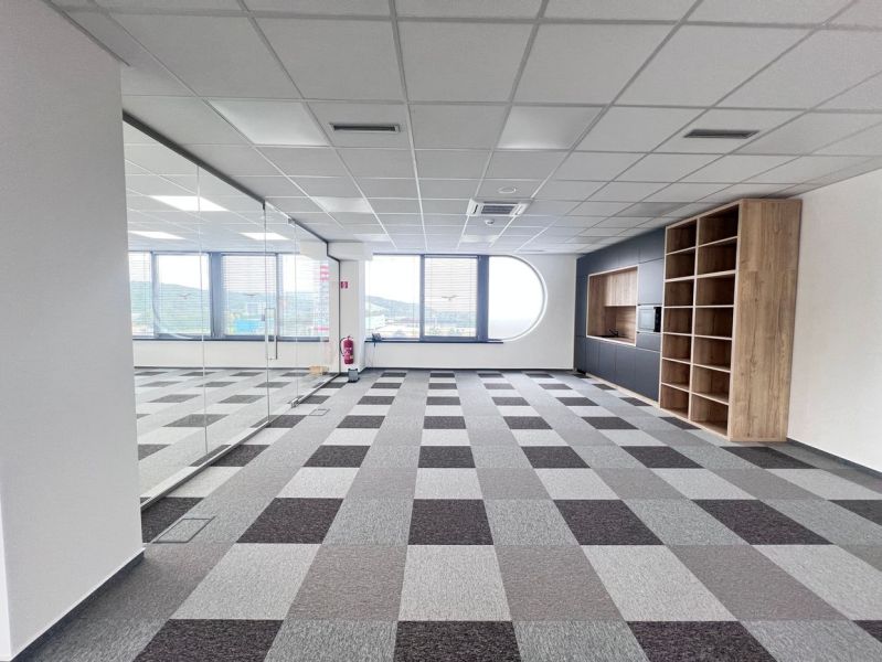 Offices with a window, a mirrored wall, built-in shelves, and a floor with a wooden decor.
