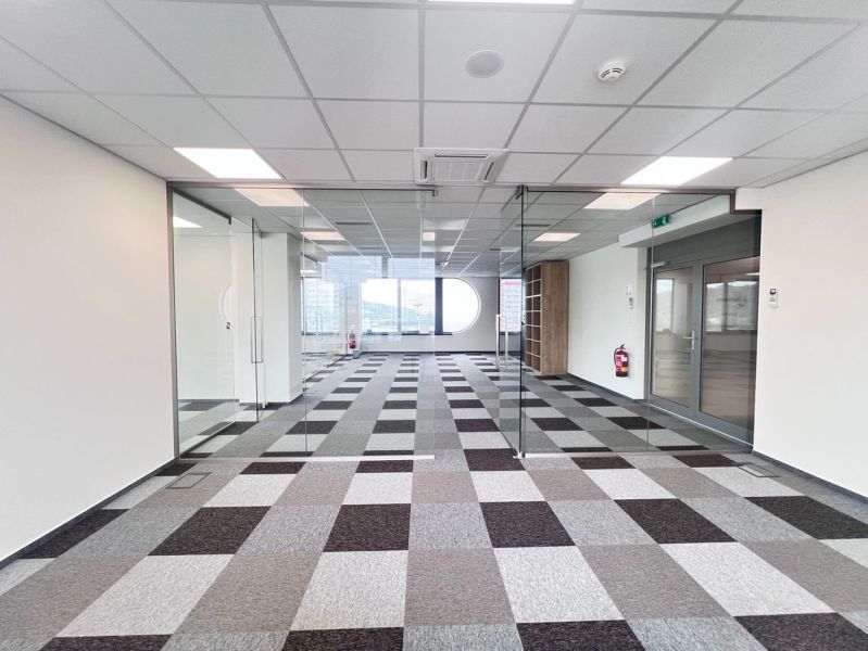 Glass office spaces with patterned carpet and large window, Offices.