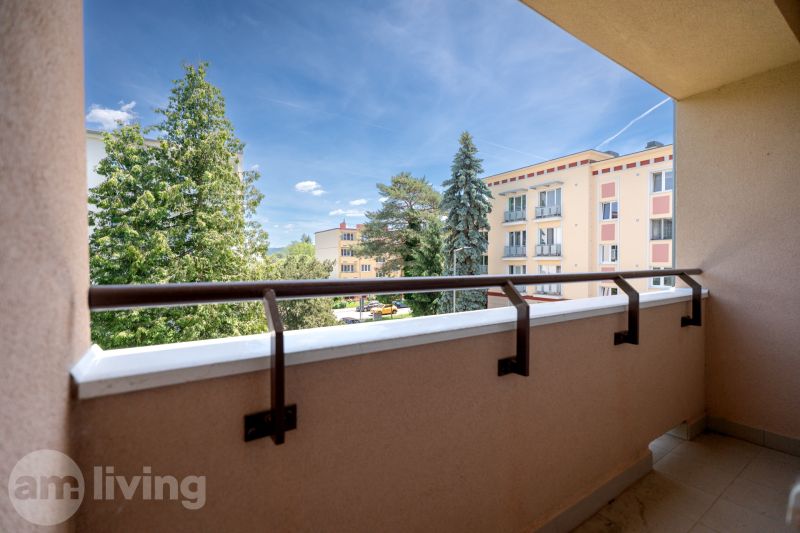 View from the balcony of a 3-room apartment on Švermova Street in Trenčín overlooking greenery and buildings.