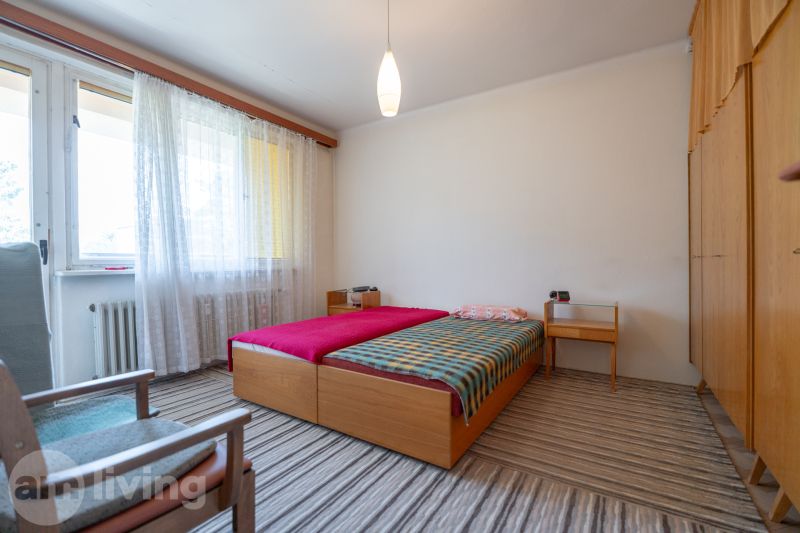 Bedroom with a light carpet and a bed in a 3-room apartment.