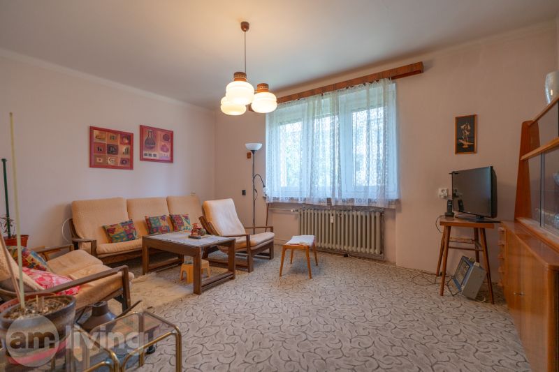 A living room in a 3-room apartment with classic furniture and a carpet, light walls.