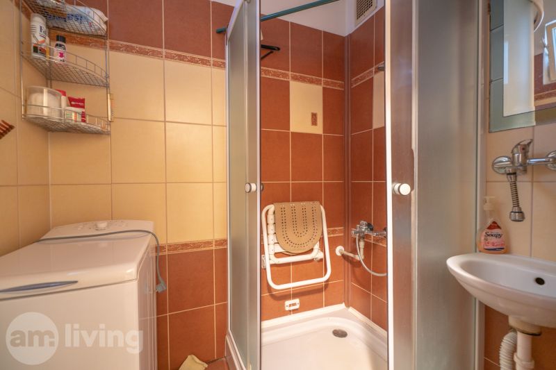 Bathroom with a washing machine, shower, and sink in a 3-room apartment.
