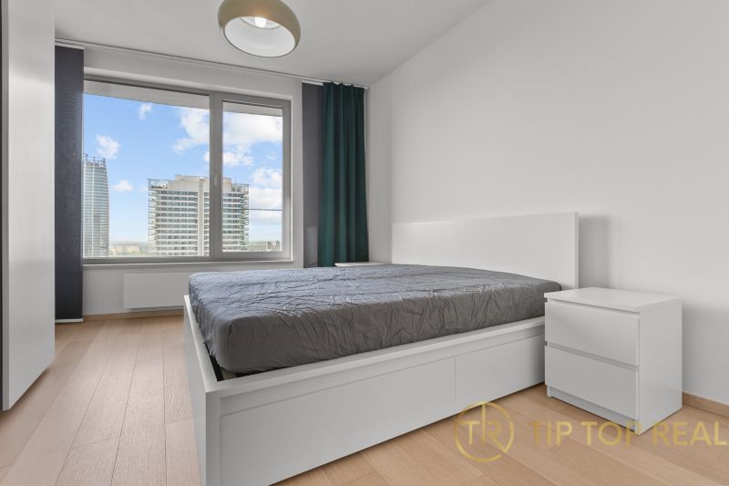 A bedroom in a 3-room apartment with a view of the city buildings on Továrenská Street.