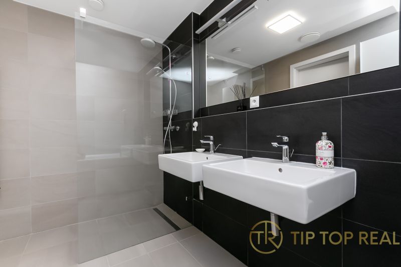 Stylish bathroom with two sinks and a shower in a 3-room apartment on Továrenská Street.