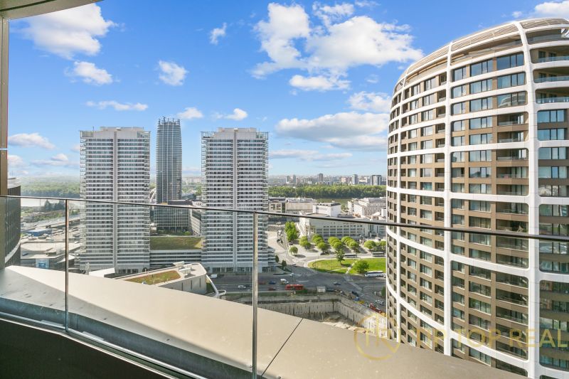 View from the balcony on Továrenská Street with modern high-rise buildings and an urban landscape.