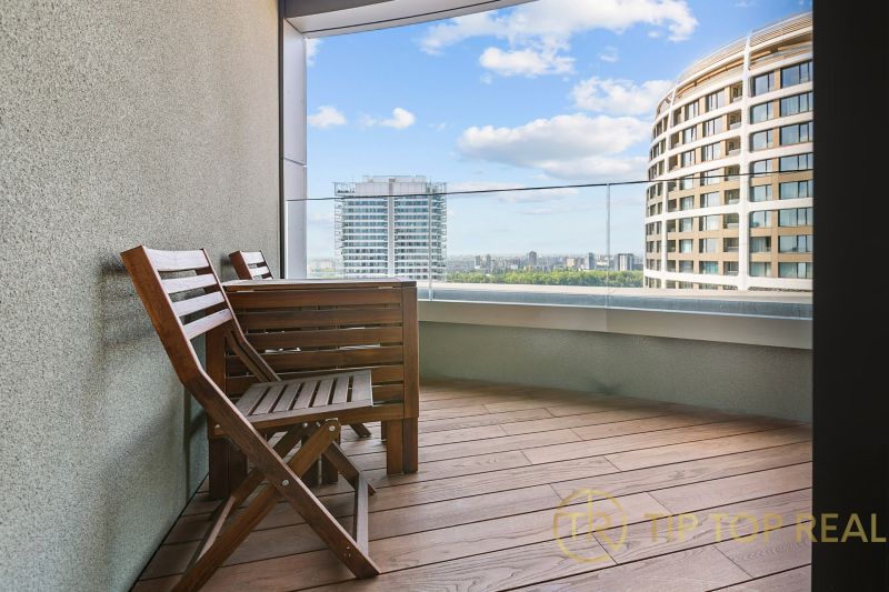 The balcony of a 3-room apartment on Továrenská Street with a view of the city and modern buildings.