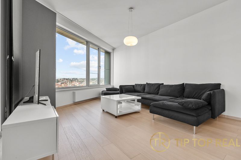 Bright living room on Továrenská Street in a 3-room apartment with a large window and a sofa.