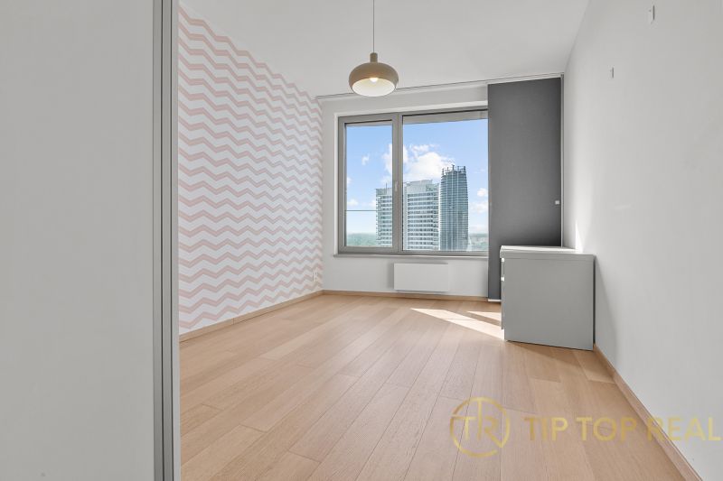 A bright room in a 3-room apartment on Továrenská Street with a view of modern architecture.