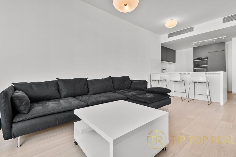 Living room of a 3-room apartment with a black sofa and a white table on Továrenská street.