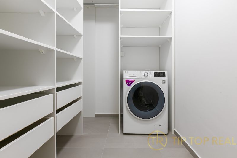 A spacious laundry room with shelves and a washing machine in an apartment on Továrenská Street.