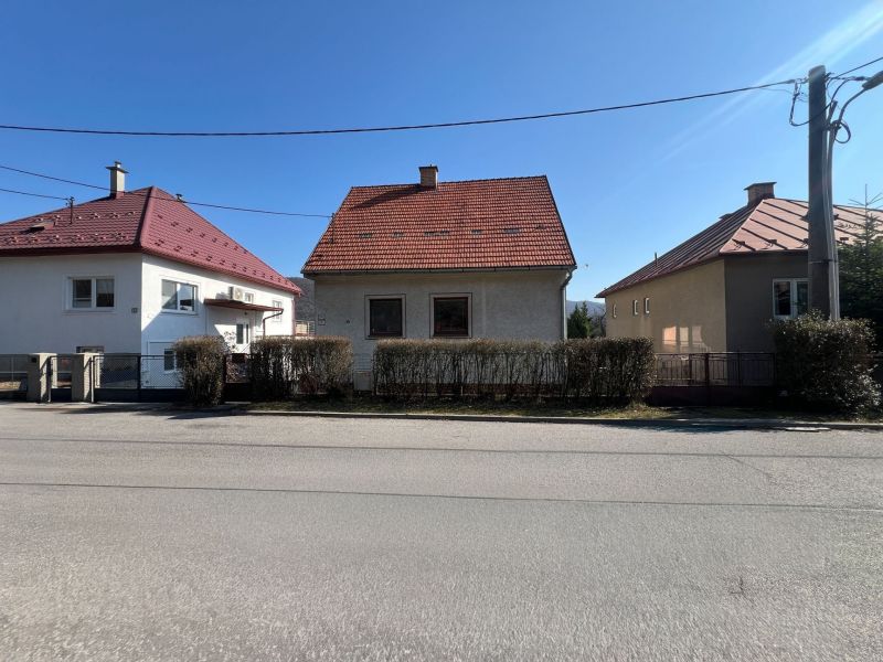 A family house in Banská Bystrica with a red roof and a hedge.