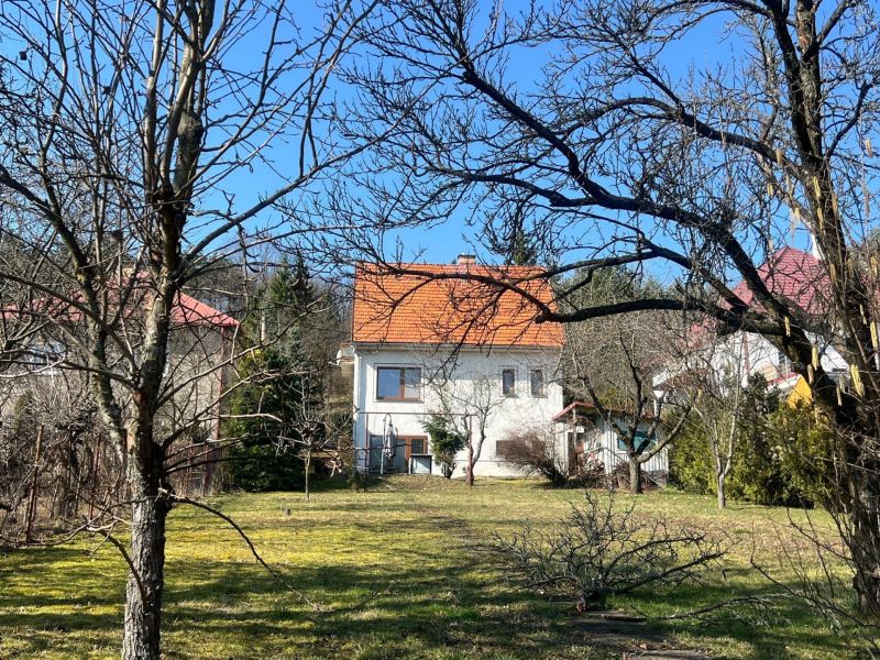 A family house in Podháj, Kráľová, surrounded by trees and lawn, with an orange roof.