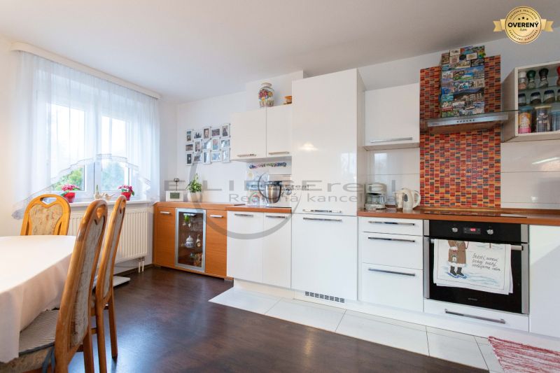 A kitchen in a family house with white cabinets and a wood-patterned floor.