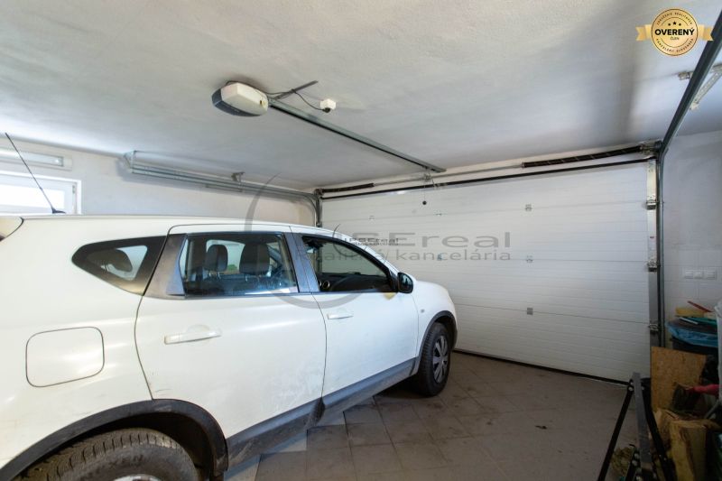 A car parked in the garage of a family house with white walls and a tiled floor.