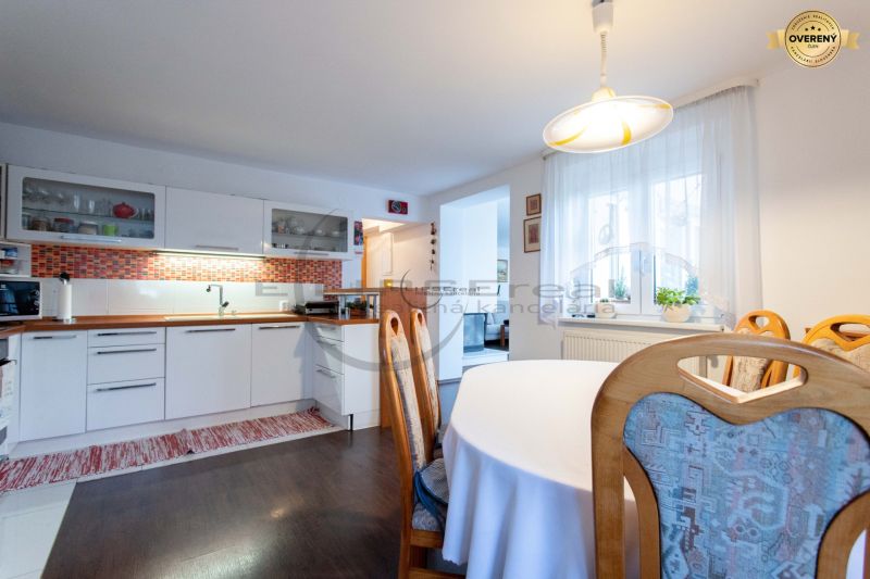 A kitchen in a family house with white cabinets, orange tiles, and a wood-patterned floor.