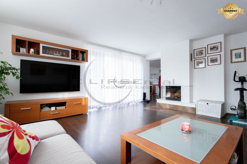 Living room in a family house with a fireplace, television, and wooden decor flooring.
