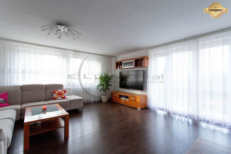 Living room in a family house with wood-patterned flooring and large windows.