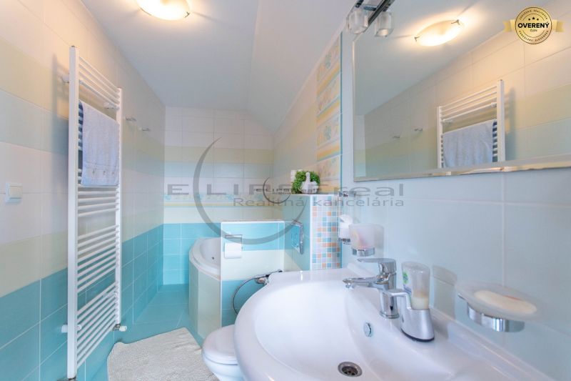 A bathroom in a family house with a white sink, bathtub, mirror, and towel rack.