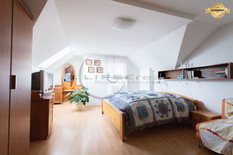 Bedroom in a family house with a wood-patterned floor, a bed, and decorations.