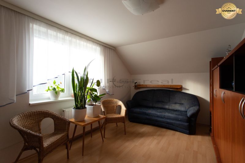 Living room with wooden floor decor, dark sofa, and wicker chairs in a family house.