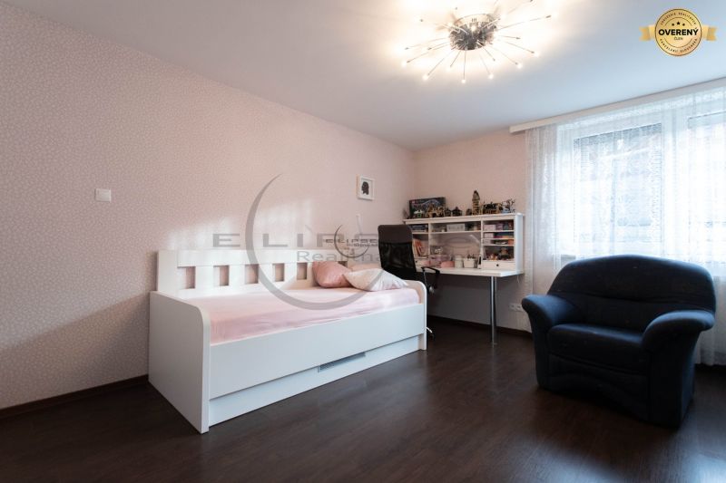 Children's room with a white bed, desk, chair, and floor with wooden decor.