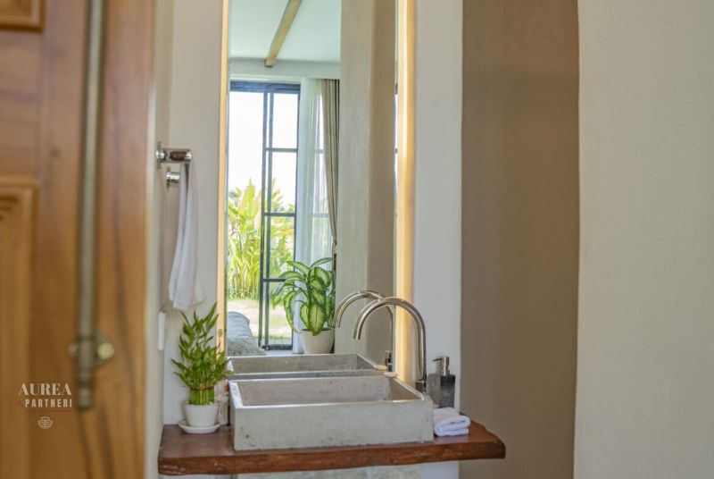 Bathroom in the villa with a mirror, sink, plants, and a view of the garden.
