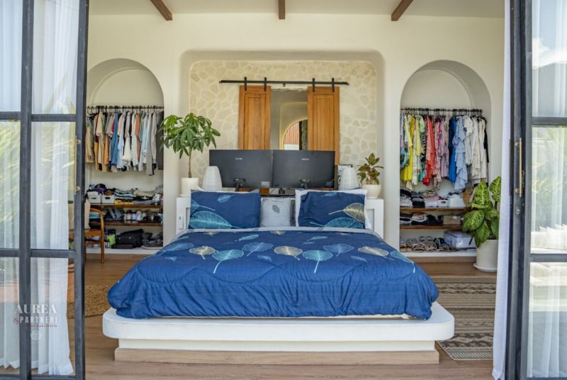 Bedroom in a villa with a wardrobe, bed, and floor with wooden decor.