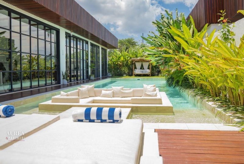 Villa in Bali with a pool, relaxing seating area, and lush tropical garden.