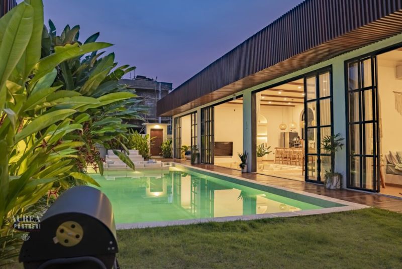 Villa in Bali with a lit pool, terrace with wooden decor, and garden.