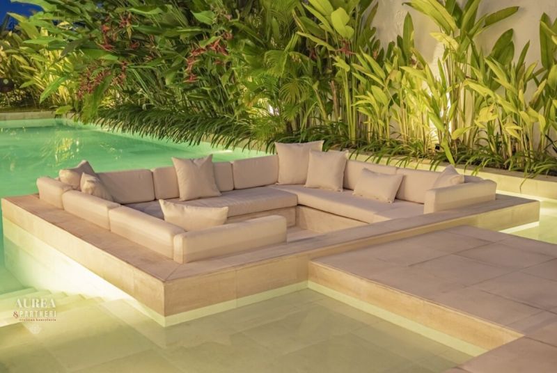 Luxurious outdoor sofa surrounded by tropical greenery by the pool in a villa in Bali.