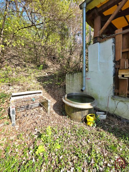 Wooden structure of the cottage and a rain barrel in the garden on 1st May Street, Krásna.