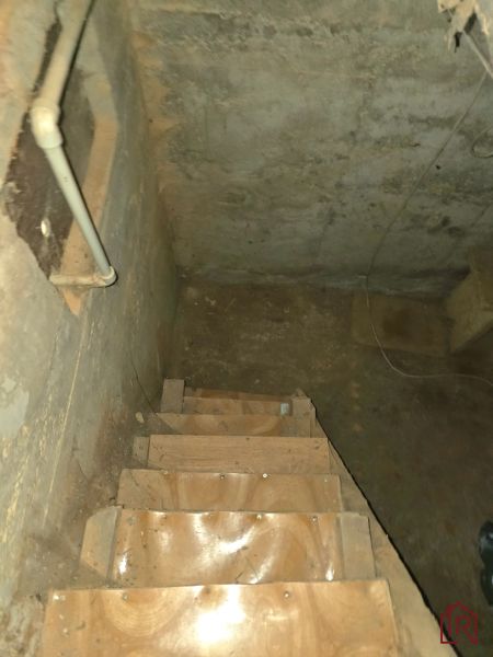 The staircase leading to the basement with walls featuring visible pipes in the Gardens.