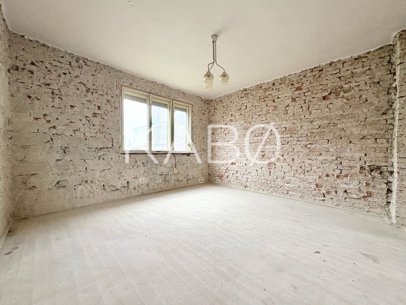 Room in a family house with brick walls and a simple chandelier.