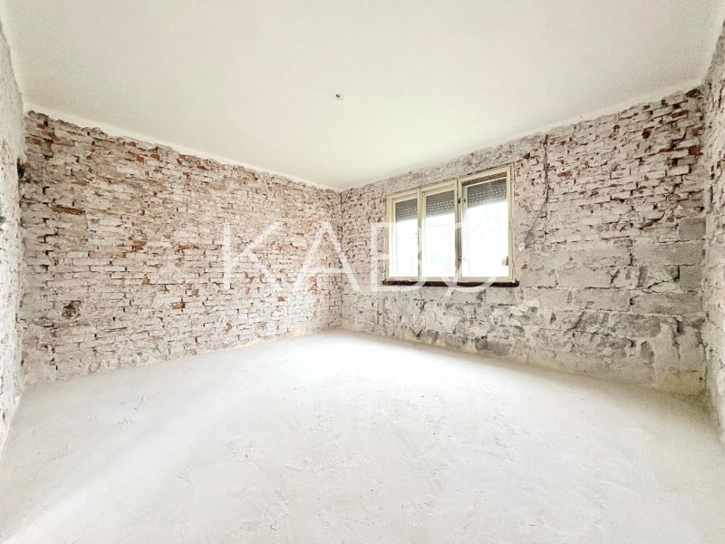 Interior of a family house with bare brick walls and a white floor.