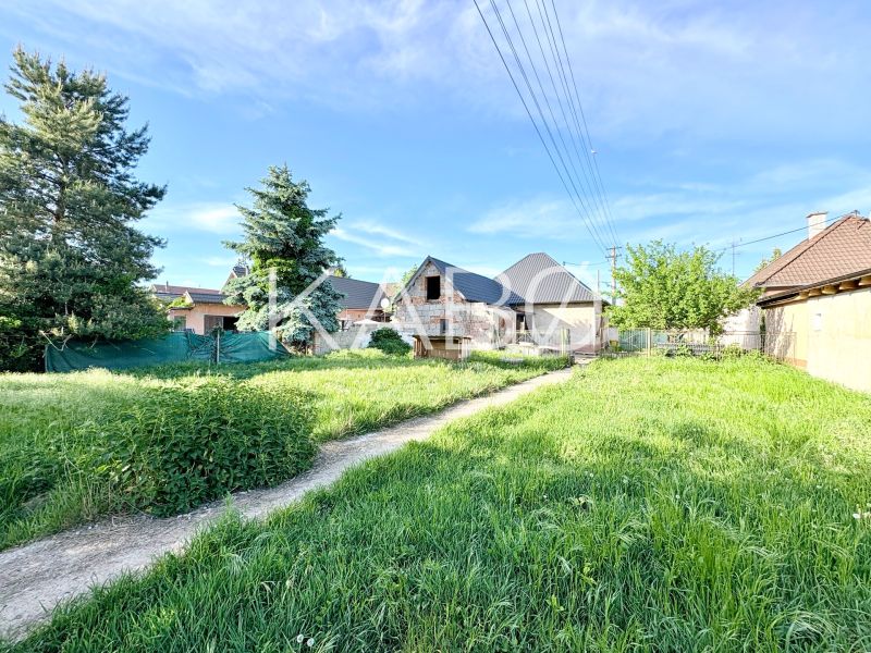 Building plot in Šoporňa with a view of the surrounding greenery and family houses.