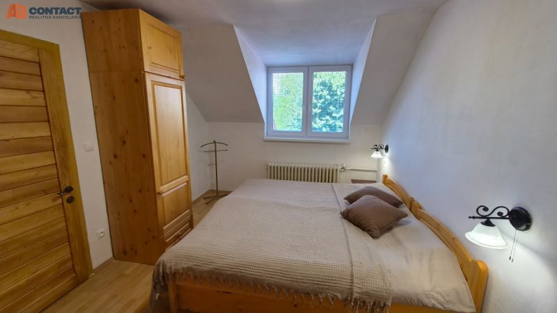 A bedroom in a 2-room apartment with wooden furniture and a wooden decor floor.