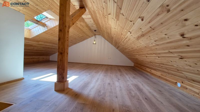 Attic space with wooden paneling and wood-patterned flooring in a 2-room apartment.