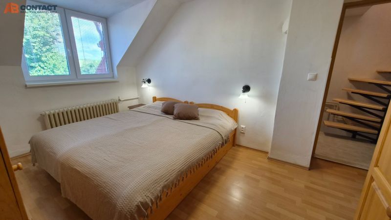 A bedroom in a two-room apartment with a double bed and a floor with a wood decor.