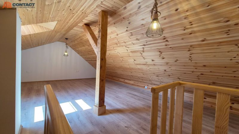 Attic space in a 2-room apartment with a wooden decor floor and wooden paneling.