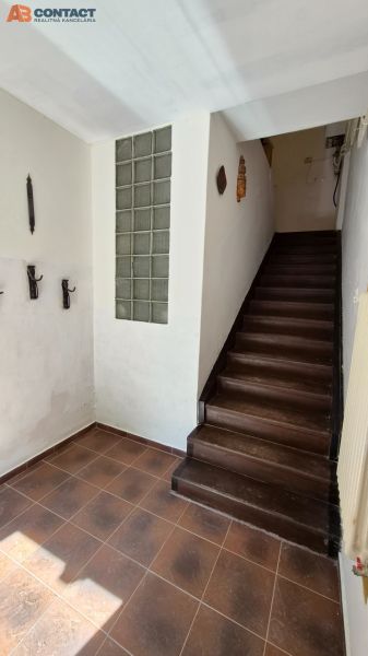 A hallway with dark stairs leading to the upper floor in a 2-room apartment.